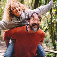 Middle-aged couple smiling outdoors and wearing dentures