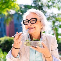 Older woman eating a salad with dentures